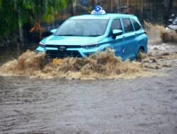 Satu unit taksi Blue Bird melintasi jalan H Naming D Bothin di Kota Depok, Jawa Barat yang tergenang banjir.