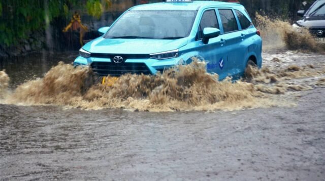 Satu unit taksi Blue Bird melintasi jalan H Naming D Bothin di Kota Depok, Jawa Barat yang tergenang banjir.