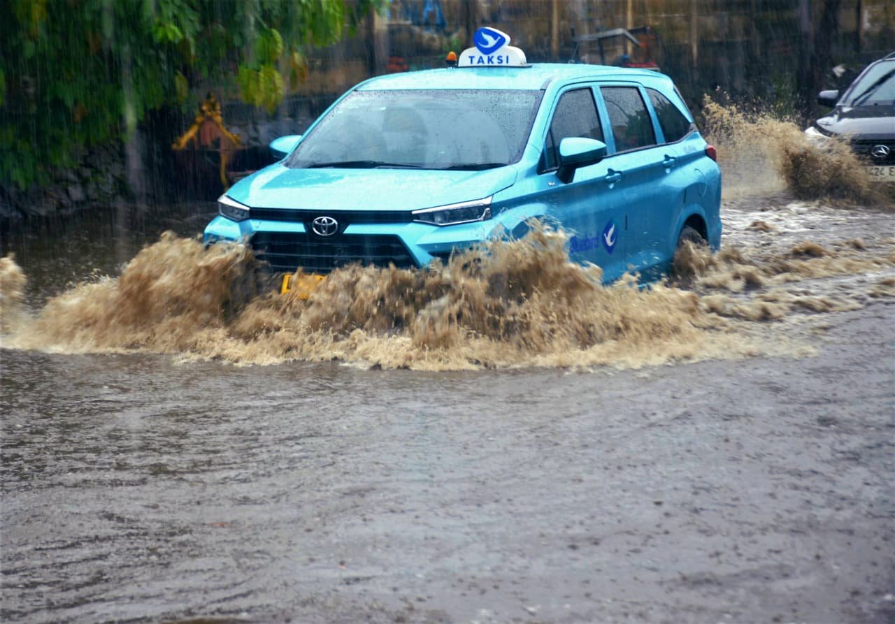 Satu unit taksi Blue Bird melintasi jalan H Naming D Bothin di Kota Depok, Jawa Barat yang tergenang banjir.